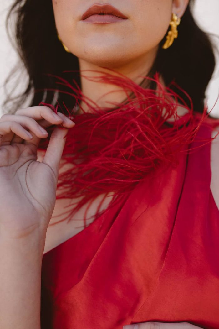 Detalle de pluma en estido de fiesta midi liso con lazada al cuello 2402 en color rojo